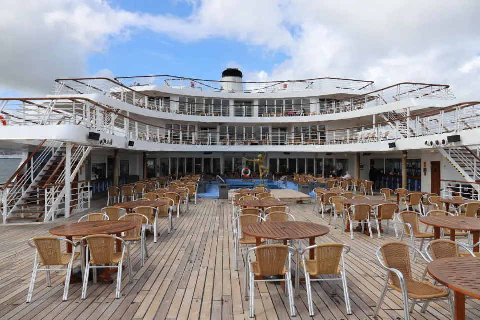 Open-air deck café with wicker chairs and tables at the stern of a cruise ship
