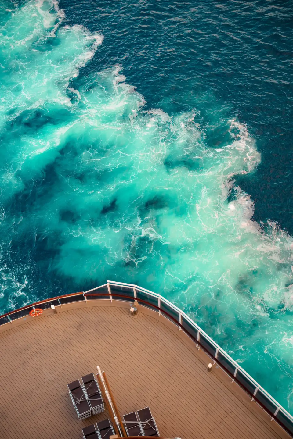 Turquoise wake churning behind the stern deck of a cruise ship