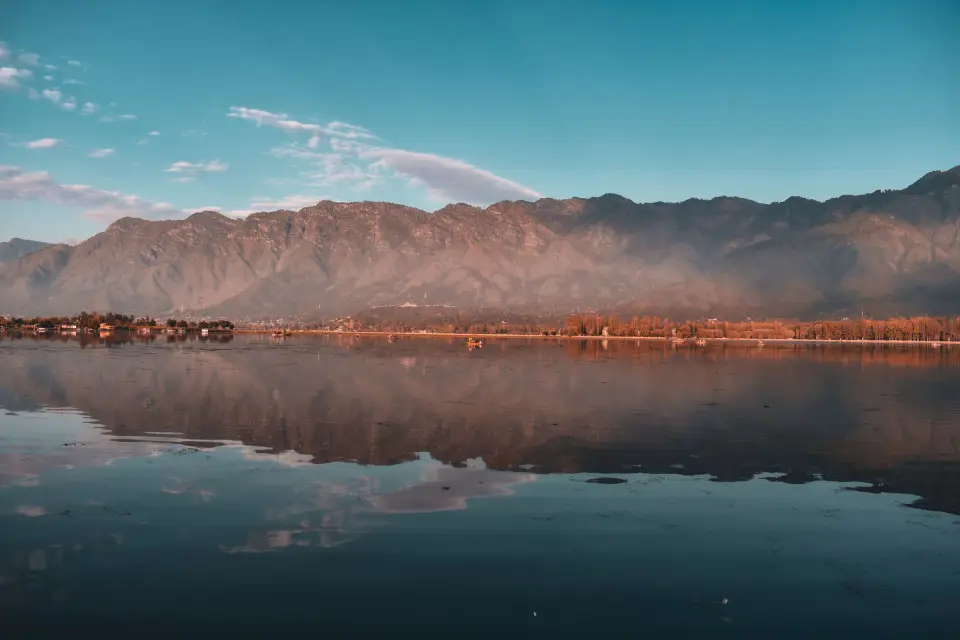 Mountains mirrored in the still water of Dal Lake at golden hour