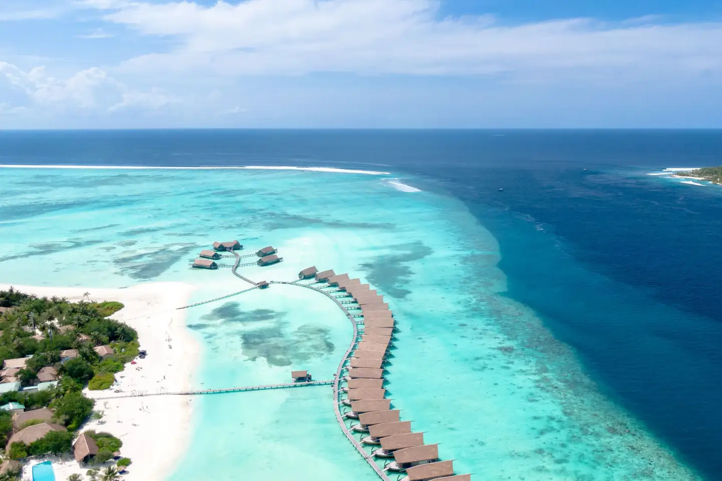 Overwater villas curving out over a turquoise lagoon in the Maldives